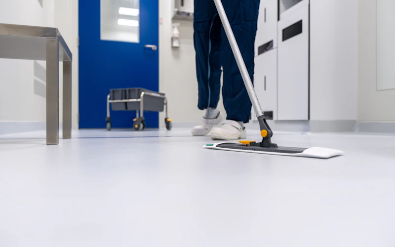 Reinigungskraft wischt den Boden in einem hellen Büro